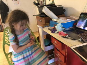 Little girl sits in a chair, hand-sewing