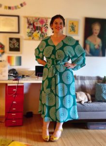 A woman wears a teal-colored, midi-length dress.