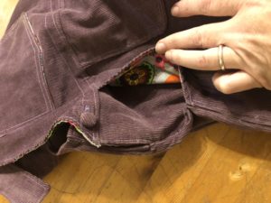 Detail of purple overalls, showing pockets lined with elephant fabric.