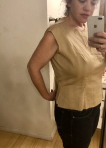 A woman wears a beige-colored fitted top.