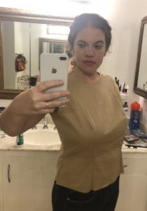 A woman wears a beige-colored fitted top.