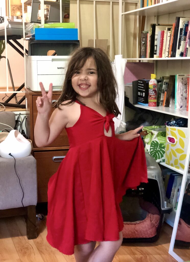 A seven-year-old girl wears a red dress.